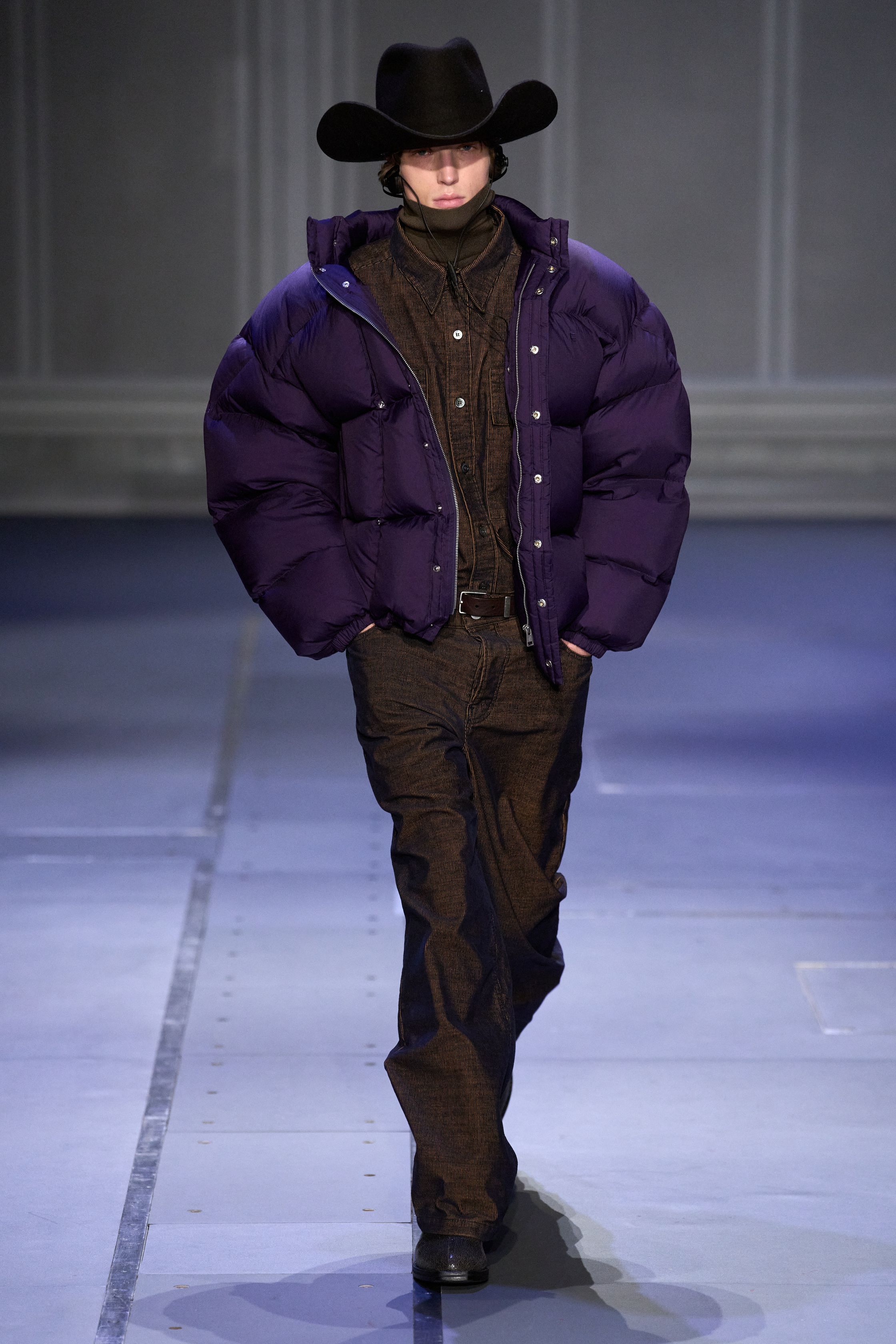 Études Studio 26FW 延续其标志性的“巴黎青年智识气质”，在克制的灰、棕、墨绿与深紫中，将街头轮廓与艺术语境并置。摄影肖像印花、皮革长风衣、渐变针织与蓬松羽绒共同构建出一种略带疏离感的城市诗意。系列并不追求强烈戏剧冲突，而是通过材质反差与比例控制，呈现介于学院派、亚文化与当代艺术之间的中间地带，体现 Études 一贯的文化策展式设计方法美-顽石频道趋势研究
